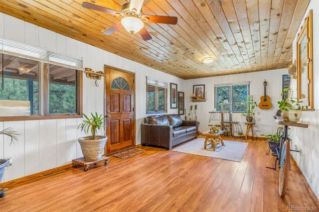 a living room with furniture a wooden floor and large windows