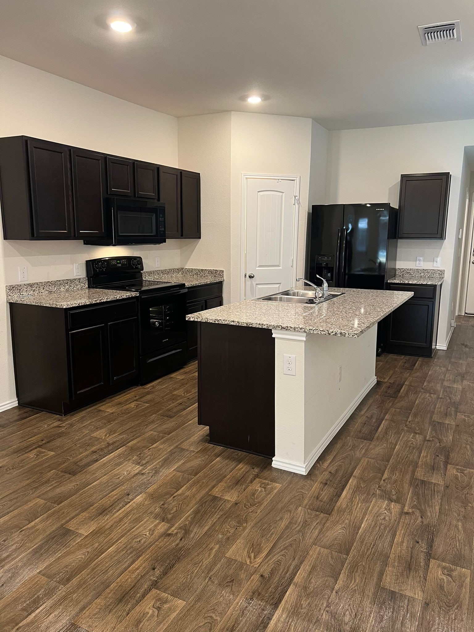 14901 Bajada Rd Manor Manor, TX 78653 - Photo 2 of 14 a kitchen with stainless steel appliances a stove top oven a sink dishwasher and a refrigerator with wooden floor
