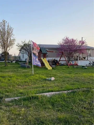 a view of a house with a big yard and large trees