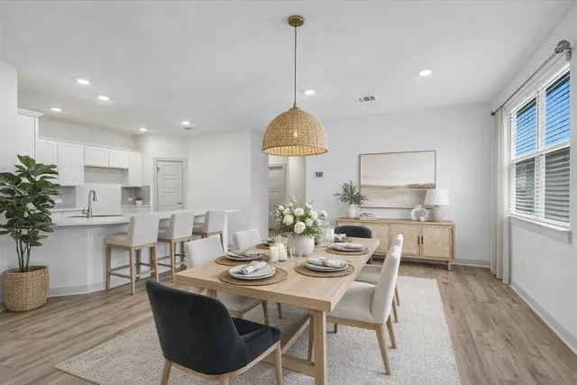 a large kitchen with stainless steel appliances a large counter top a stove a sink dishwasher and a refrigerator with wooden floor