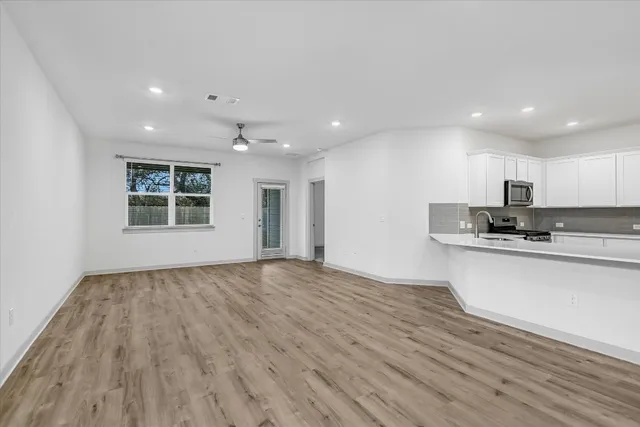 a large kitchen with wooden floors and white stainless steel appliances