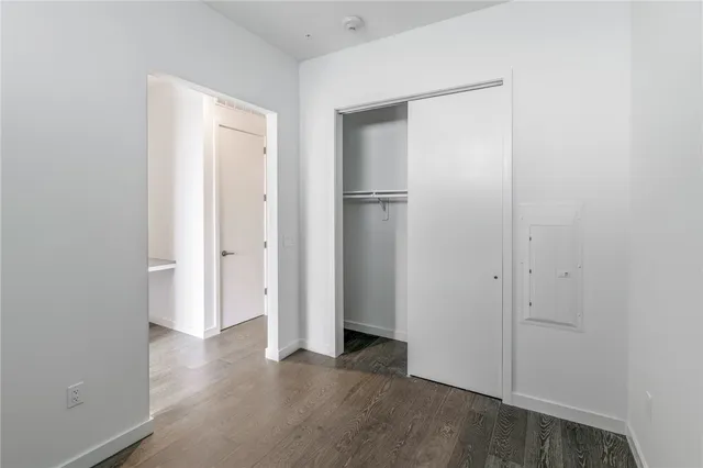 a view of an empty room with closet and wooden floor
