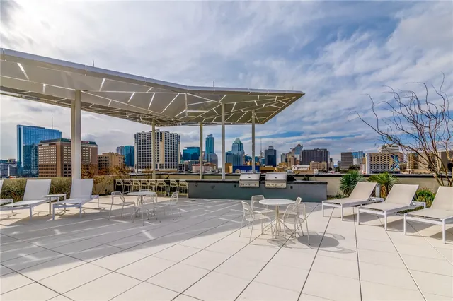 a view of a patio with table and chairs potted plants and a large window