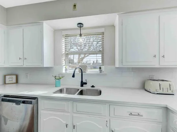 a kitchen with stainless steel appliances a sink a window and cabinets