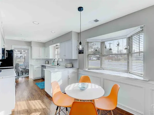 a kitchen with stainless steel appliances kitchen island granite countertop a dining table chairs and a refrigerator