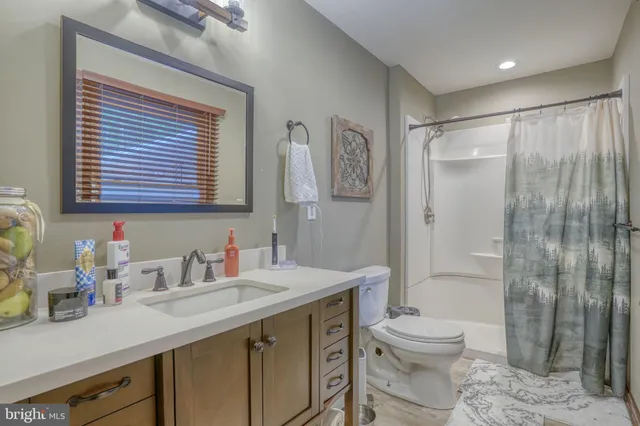 a bathroom with a granite countertop sink toilet a large mirror a shower and a window