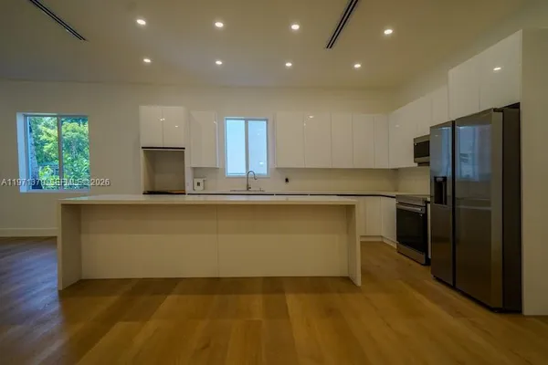a large kitchen with kitchen island a sink stainless steel appliances and a window