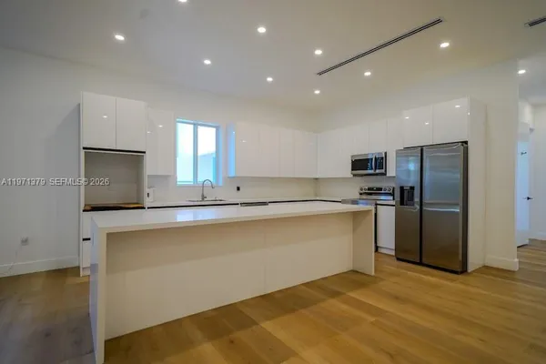 a large kitchen with stainless steel appliances a large counter top a stove a refrigerator and a sink