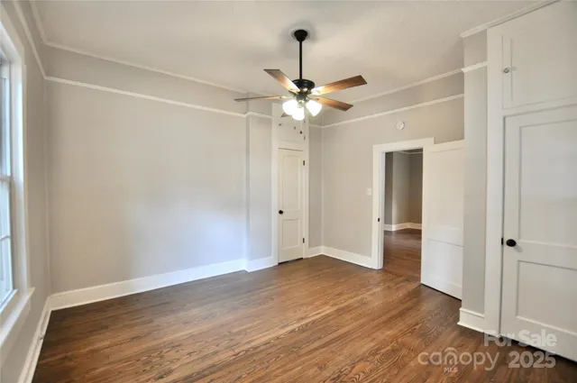 an empty room with wooden floor ceiling fan and window