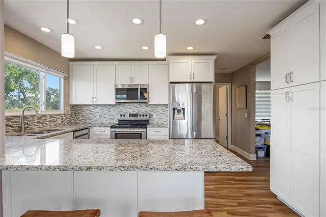 a kitchen with stainless steel appliances granite countertop a refrigerator sink and stove
