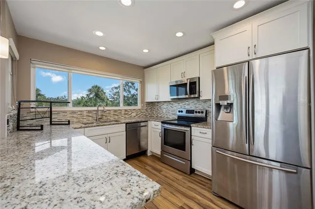 a kitchen with stainless steel appliances granite countertop a refrigerator a stove and a sink