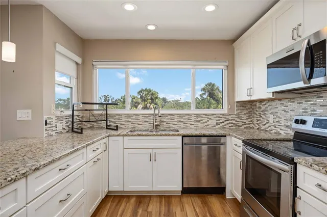 a kitchen with stainless steel appliances granite countertop a sink and cabinets with wooden floor