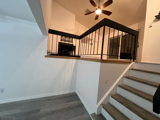 a view of staircase with wooden floor and fan
