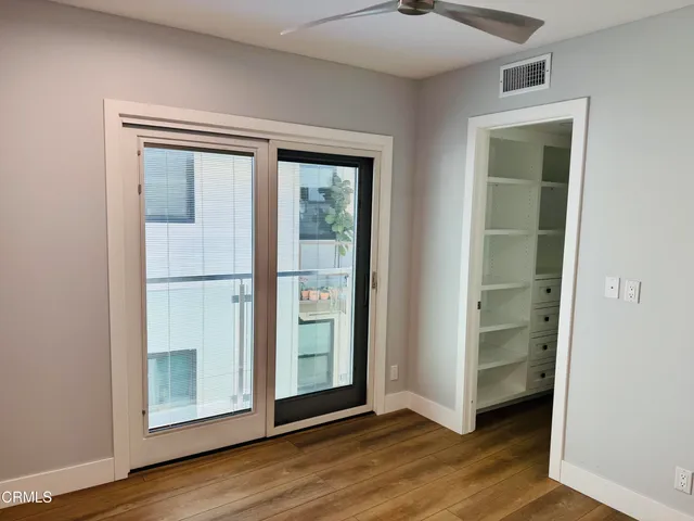 an empty room with wooden floor closet and windows