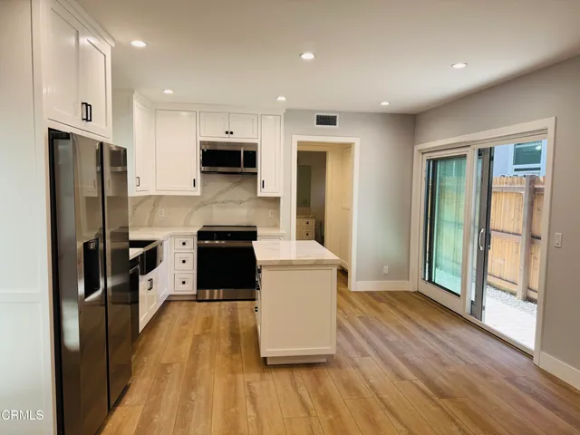 a large kitchen with a large counter top stainless steel appliances and wooden floor