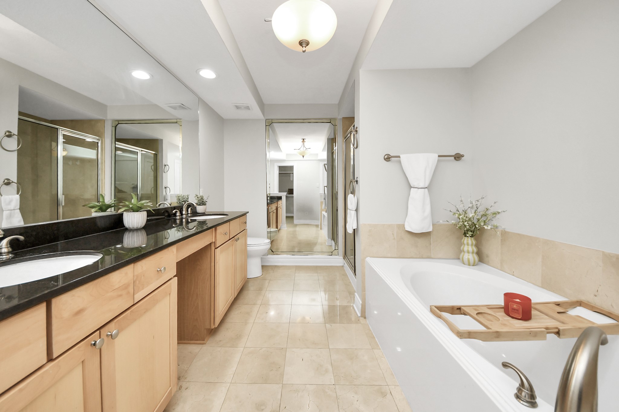 5909 Katy Street Houston, TX 77007 - Photo 21 of 34 Primary bath featuring a double vanity with granite countertops, a soaking tub, and a separate glass-enclosed shower. The neutral tile flooring and ample lighting.