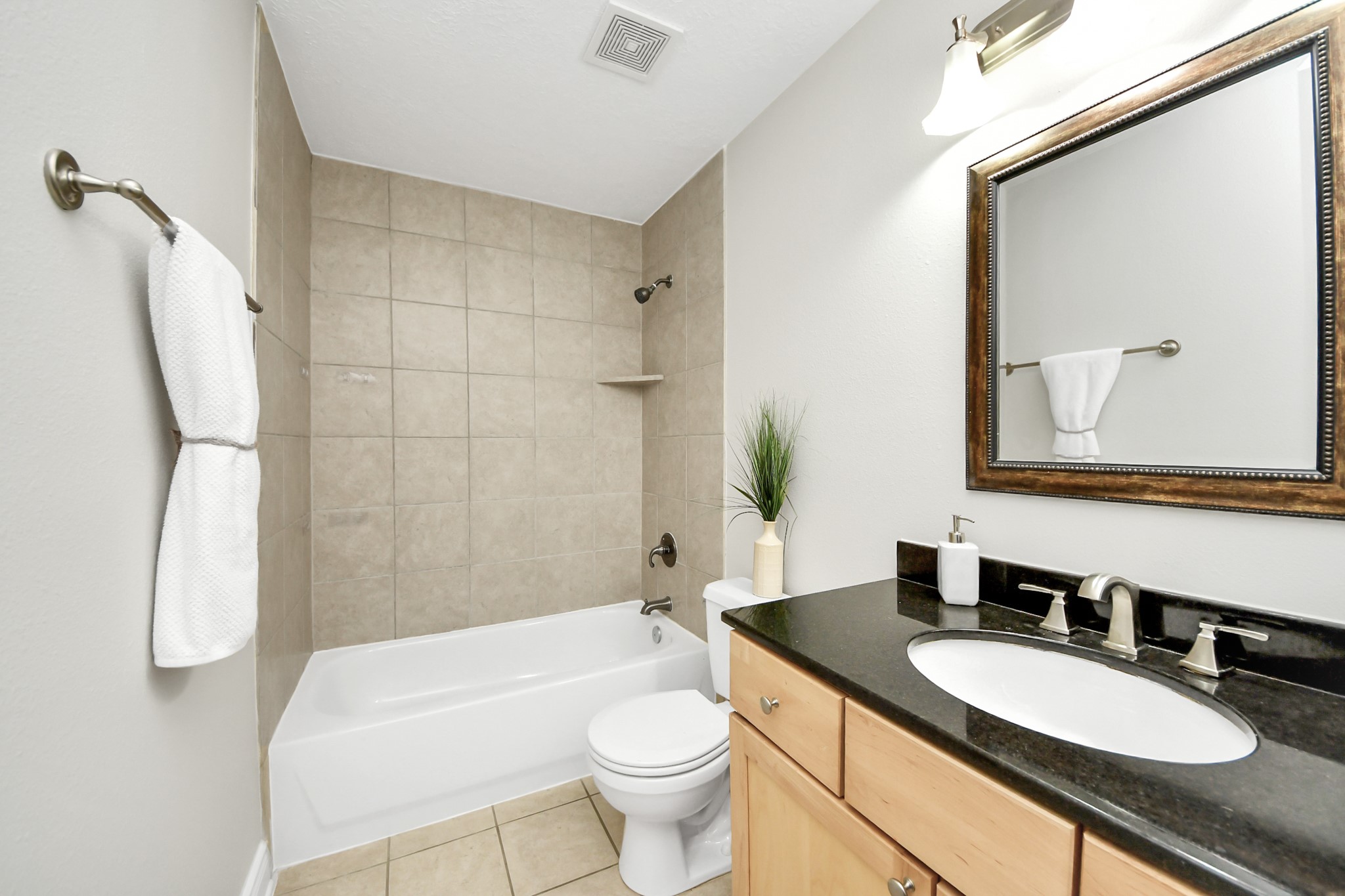 5909 Katy Street Houston, TX 77007 - Photo 28 of 34 Secondary bathroom has sleek black granite countertop, wooden cabinetry, framed mirror, tile up to the ceiling and stylish fixtures.