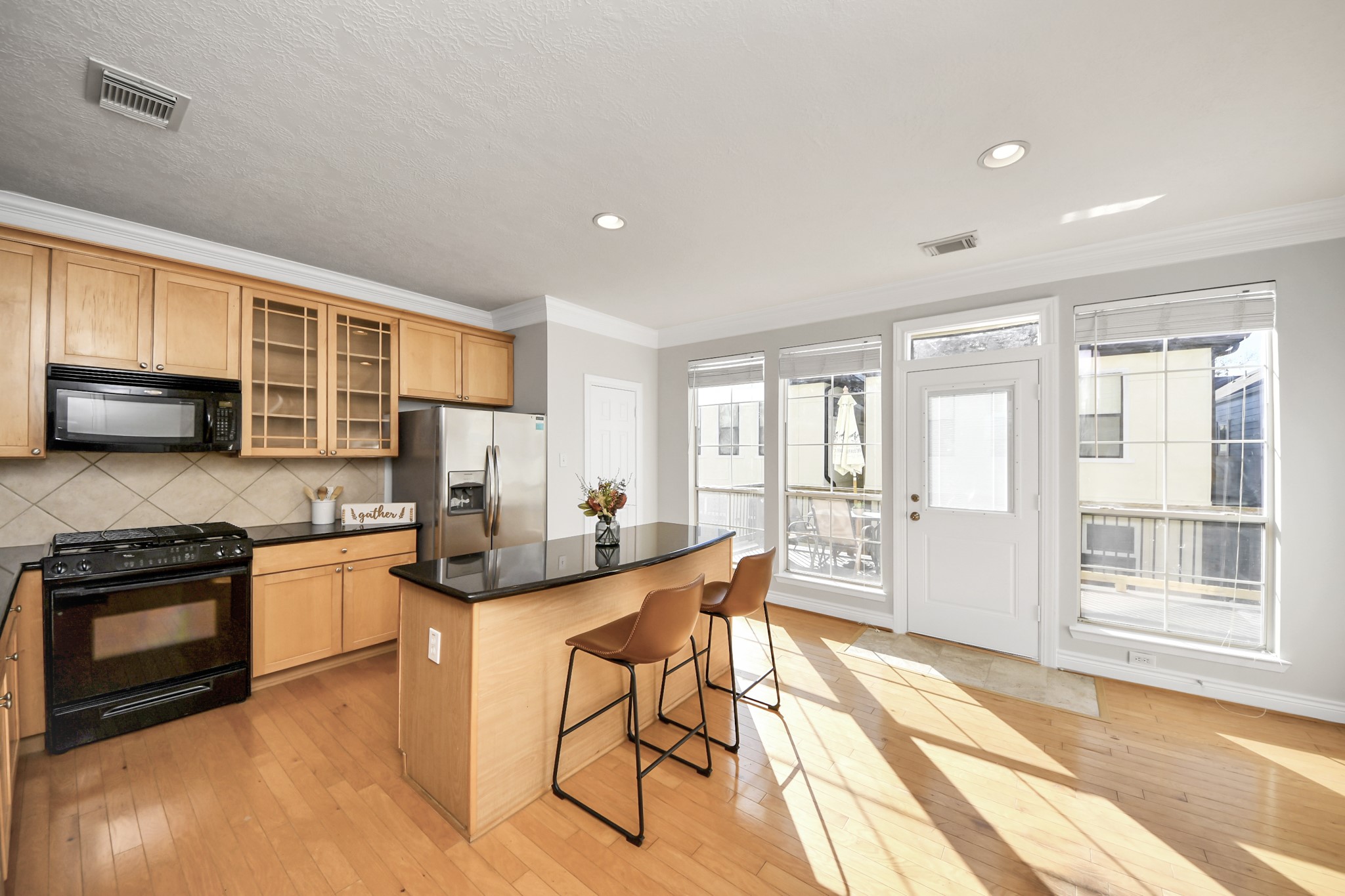 5909 Katy Street Houston, TX 77007 - Photo 7 of 34 Open concept kitchen with access to the spacious deck, features crown molding, sleek black granite countertops, light wood glass front cabinetry and is filled with natural light.