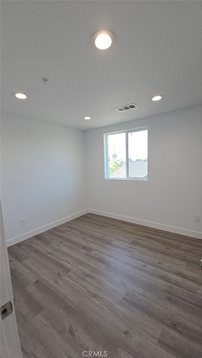 10413 Avalon Boulevard Los Angeles, CA 90003 - Photo 8 of 23 an empty room with wooden floor and windows