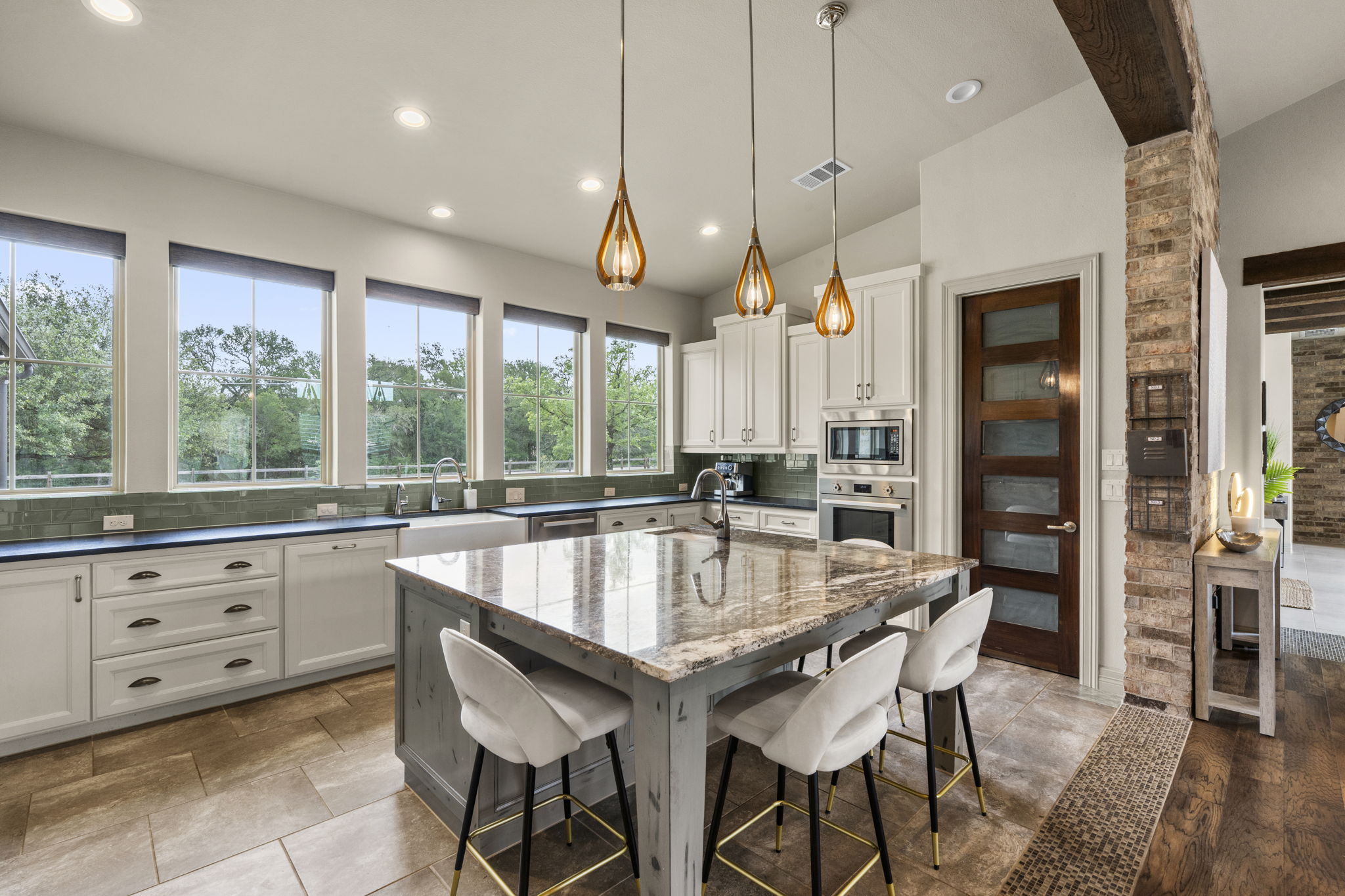16202 Remuda Trail Buda, TX 78610 - Photo 8 of 40 The well-appointed kitchen features a large island with a stone countertop, white cabinetry, and stainless steel appliances