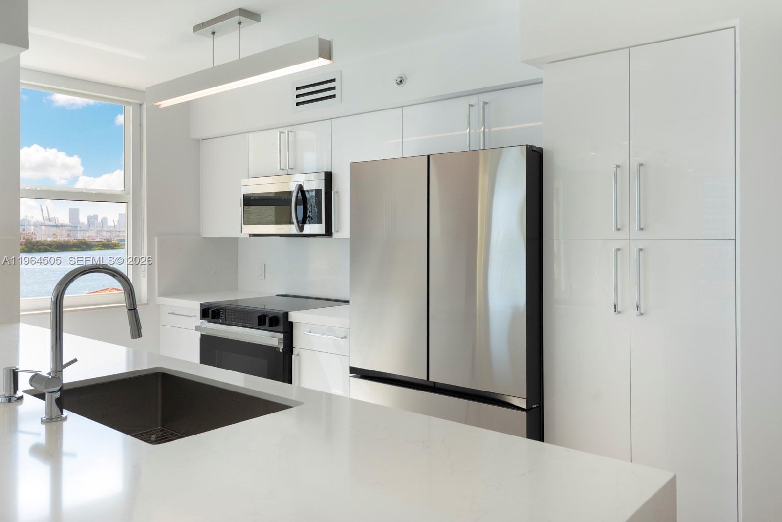 90 Alton Road, Unit 902 Miami Beach, FL 33139 - Photo 13 of 34 a kitchen with granite countertop a refrigerator and a stove top oven