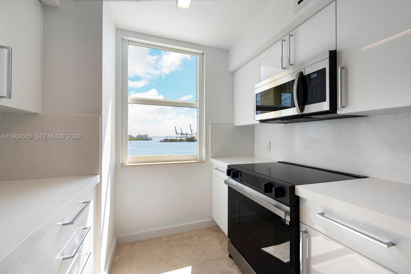 90 Alton Road, Unit 902 Miami Beach, FL 33139 - Photo 6 of 34 a utility room with stainless steel appliances white cabinets and a stove top oven