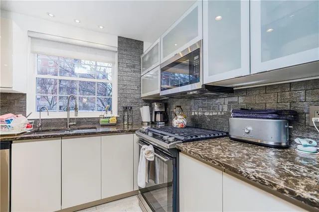 a kitchen with stainless steel appliances granite countertop a sink stove and cabinets