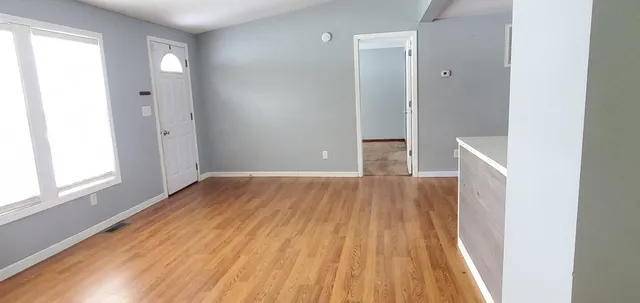 a view of an empty room with wooden floor and a window