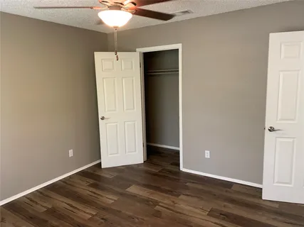 an empty room with wooden floor and fan
