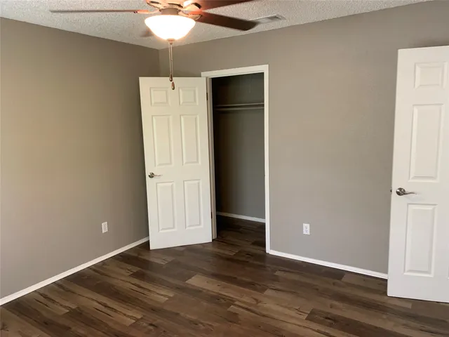 an empty room with wooden floor and fan