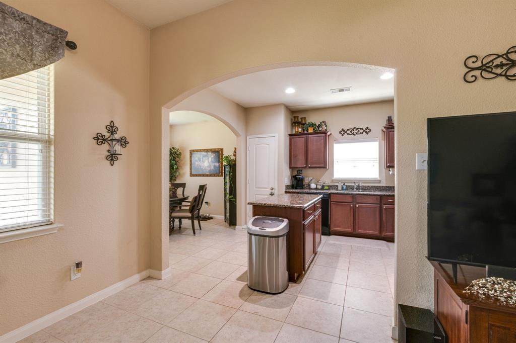 1853 Olive Lane Anna, TX 75409 - Photo 8 of 23 Kitchen featuring arched walkways, dark stone counters, a textured wall, a center island, and light tile patterned floors