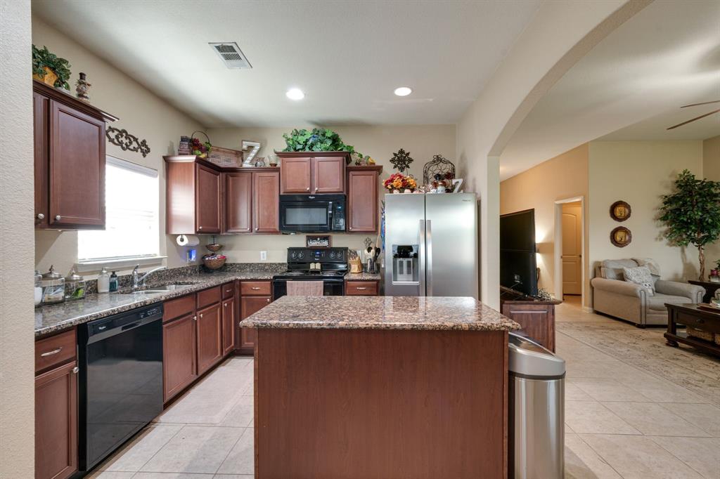 1853 Olive Lane Anna, TX 75409 - Photo 23 of 23 Kitchen featuring black appliances, a kitchen island, dark stone countertops, open floor plan, and recessed lighting