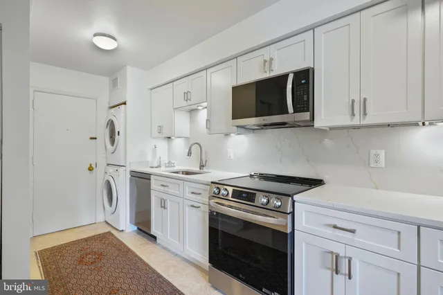a kitchen with stainless steel appliances granite countertop white cabinets a stove a microwave and a sink