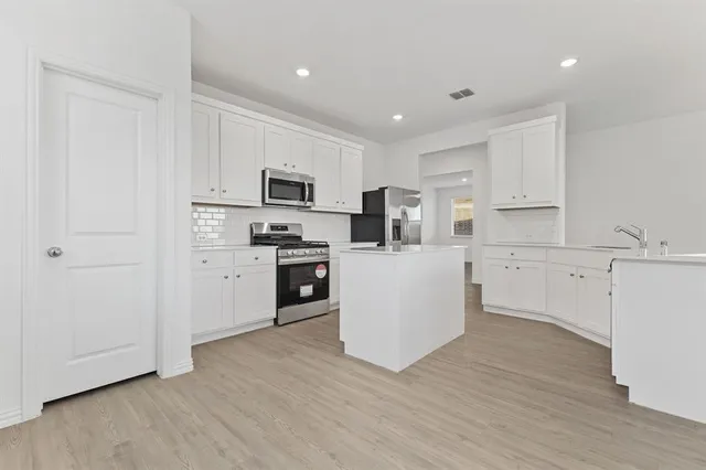 a kitchen with white cabinets and stainless steel appliances