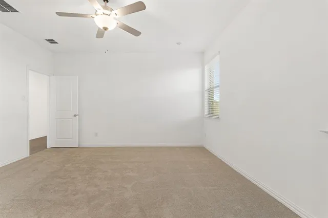 an empty room with a window and a fan