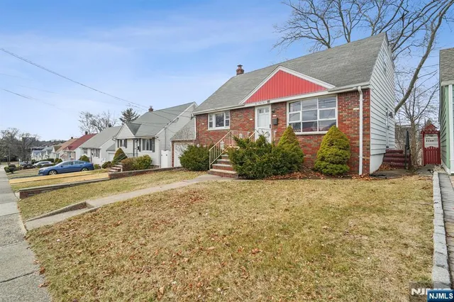 a front view of house with yard and trees in the background