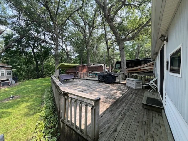 a view of house with deck outdoor seating and covered with trees
