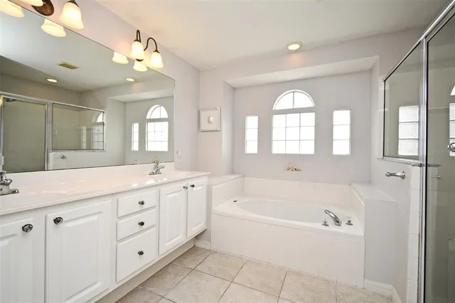 a spacious bathroom with a granite countertop tub a double vanity sink and a mirror