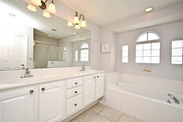 a spacious bathroom with a granite countertop tub a double vanity sink a window and a mirror