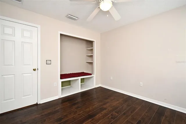 an empty room with wooden floor closet and windows