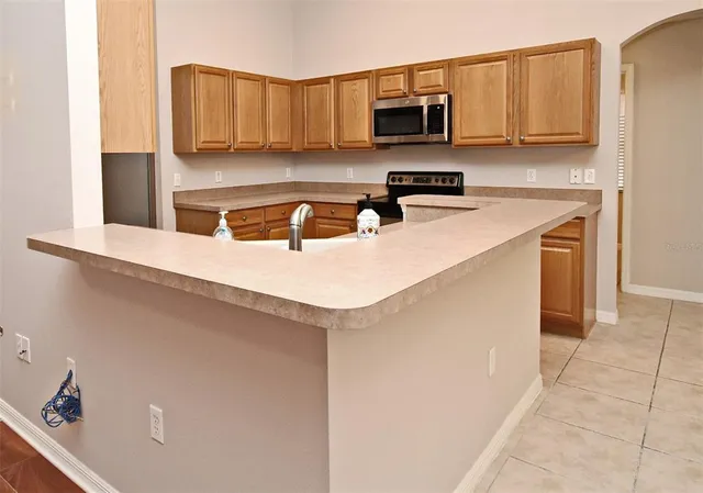 a kitchen with stainless steel appliances a sink a stove a microwave a sink a refrigerator and cabinets