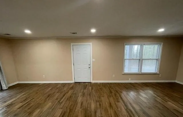 an empty room with wooden floor and windows