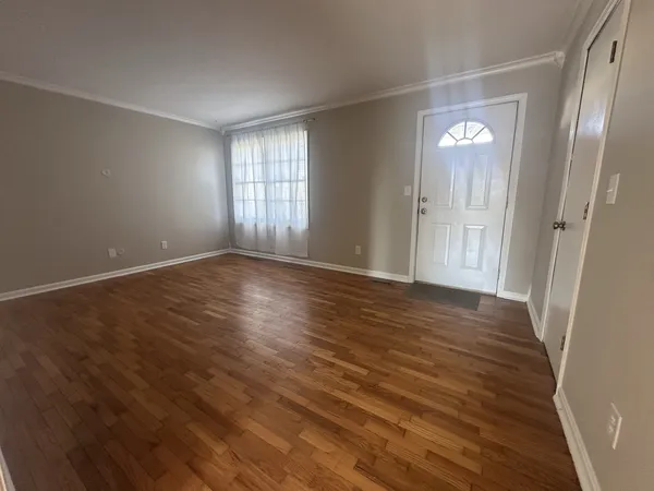 a view of an empty room with wooden floor and a window
