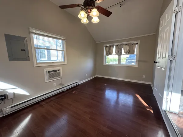 a view of an empty room with wooden floor and a window