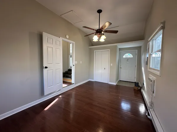 a view of an empty room with window and wooden floor