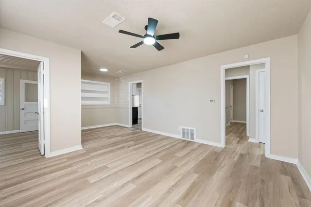 a view of empty room with wooden floor and ceiling fan