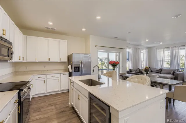 a kitchen with stainless steel appliances kitchen island granite countertop a sink dishwasher and white cabinets with wooden floor