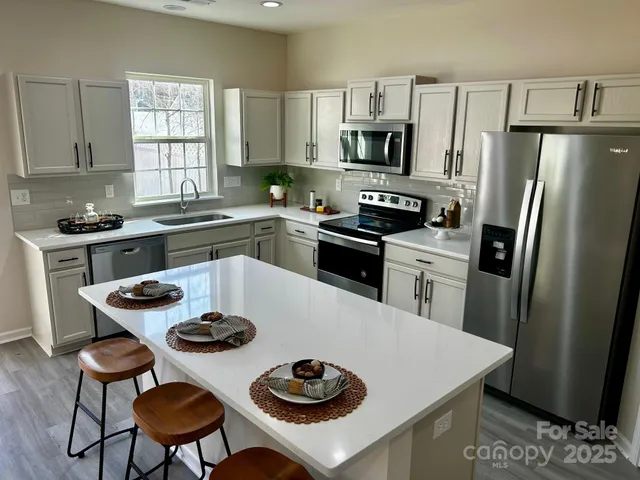 a kitchen with stainless steel appliances a table chairs stove and refrigerator