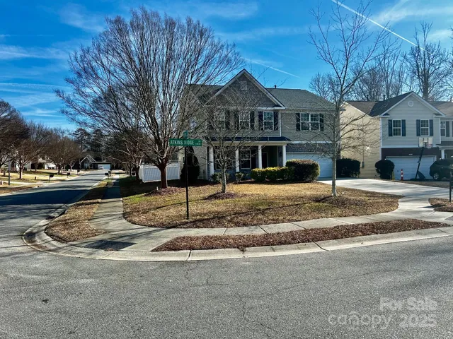 a view of a white house with a large tree