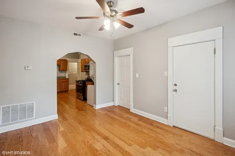 a view of a room with wooden floor a ceiling fan and a kitchen space